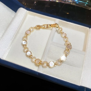 Détail d'un bracelet doré de luxe avec nacre et zircons dans un écrin bleu marine