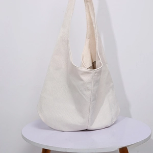 Detail of white canvas hobo bag showing minimalist integrated strap and spacious design
