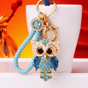 Detailed macro view of a blue rhinestone owl keychain with a braided leather strap and gold clip