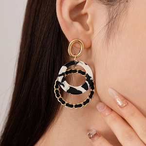 Close-up of vintage resin hoop earrings featuring gold chain weave and leopard pattern