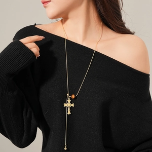 Tiger eye cross pendant on a long gold chain necklace worn by a fashion model