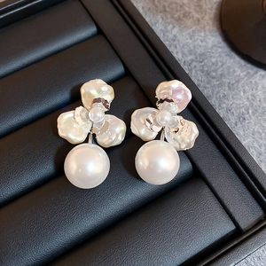 Macro shot of silver pearl flower earrings with baroque petals on black leather case