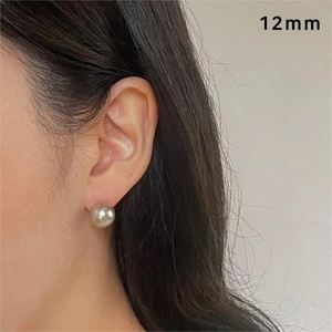 Close-up of 12mm champagne pearl stud earring on model's ear showing actual scale