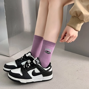 Purple ribbed mid-tube socks with embroidered sports label worn with sneakers