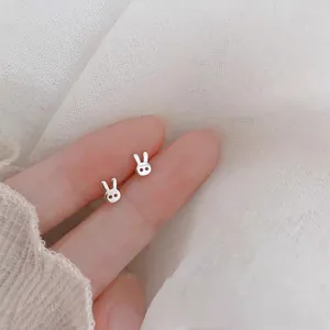 Close-up of minimalist S925 sterling silver rabbit stud earrings on fingertips