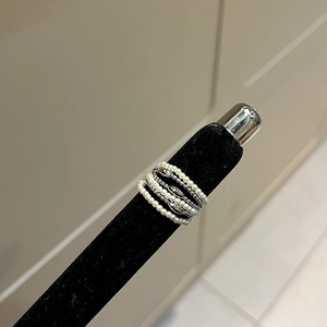 Detail of vintage square pearl and silver ring set displayed on black velvet ring stand