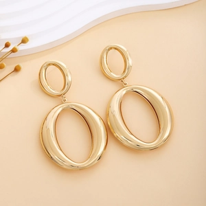 Close-up of golden double oval drop earrings with polished metallic texture