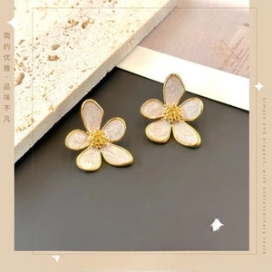 Macro shot of white sparkling flower earrings with gold petals and brass core