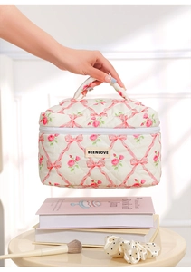 Detailed view of hand holding quilted floral makeup bag with pink bow pattern and handle