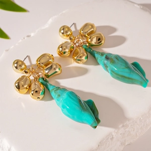 Irregular gold studs and green acrylic conch shell earrings on a stone display