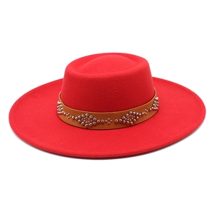 Detail of red wool felt fedora featuring a brown band with silver metal rivet patterns