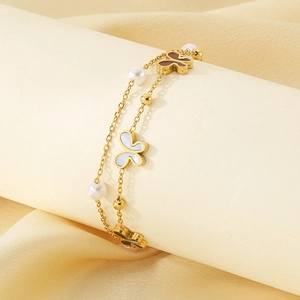 Detail view of double-layer gold butterfly bracelet with white pearls and charms