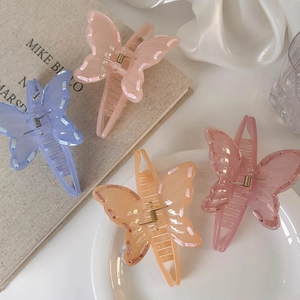 Set of four colorful bow hair claws in pink, blue, orange, and rose on a chic beige background