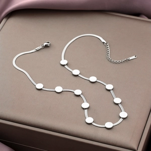 Detailed macro view of silver snake chain necklace with flat disc charms and lobster clasp
