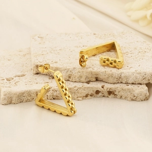 Vintage golden triangular U-shaped stainless steel earrings on natural stone background