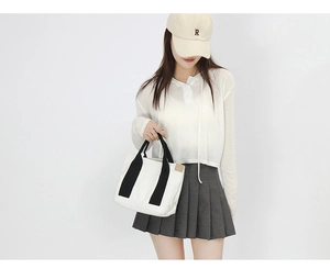 Minimalist black and white contrast canvas tote bag styled with a pleated skirt