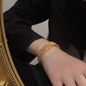 Close-up of a five-layer gold plated beaded cuff bracelet on a female model's wrist