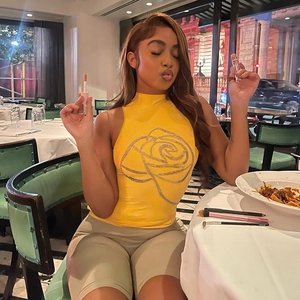 Détail d'un haut sans manches jaune à col montant avec motifs de roses en strass