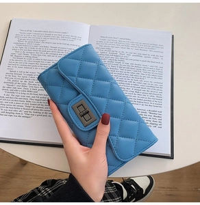 Detailed close-up of blue quilted texture and metal twist lock on a long wallet
