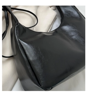 Detailed view of glossy black faux leather surface and clean stitching on the shoulder bag