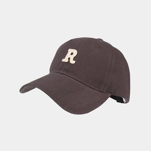 Dettaglio del ricamo a spugna della lettera R su cappellino in cotone marrone scuro