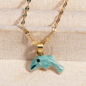 Macro shot of light blue enamel dolphin pendant on a fine golden necklace chain