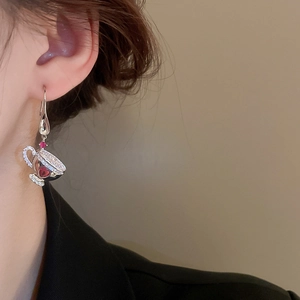 Detail of coffee cup earrings with white zircon and a red heart gemstone on model