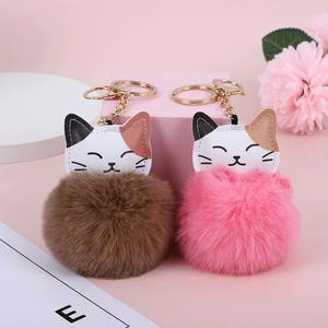 Cute lucky cat keychains with brown and pink faux rabbit fur balls on soft background