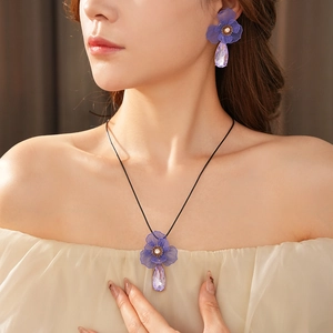 Elegant model wearing purple flower jewelry set with crystal teardrop necklace and earrings