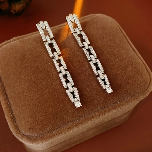 Gros plan de boucles d'oreilles chaîne en argent et zircon sur une boîte en velours