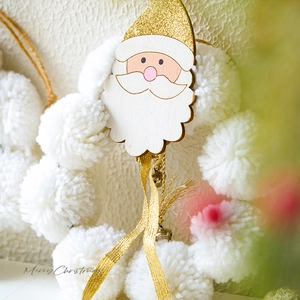 White pom-pom Christmas wreath featuring a wooden Santa head with gold glitter hat