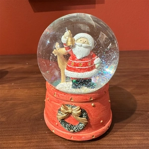 Close-up of a Christmas snow globe music box with Santa and reindeer on a wooden table
