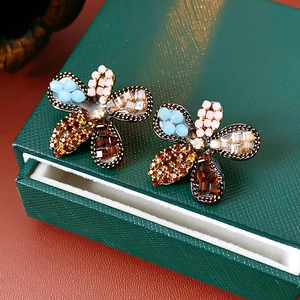 Close-up of vintage flower earrings with colorful crystals on dark green jewelry box