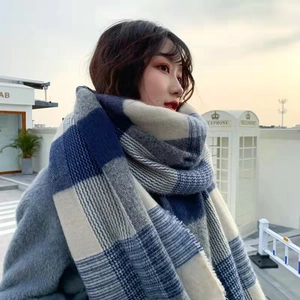 Detail of blue and beige checkered thick scarf with soft tassels for winter warmth