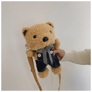 Detail of cute brown plush bear bag wearing denim overalls and a checkered bowtie