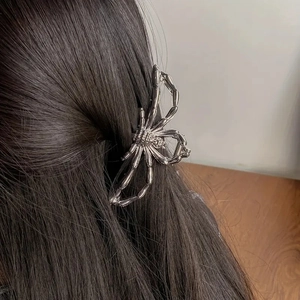 Pince à cheveux araignée argentée portée sur des cheveux longs foncés, vue de côté