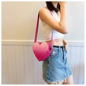 Détail du sac bandoulière en forme de cœur avec dégradé de rose et clous métalliques