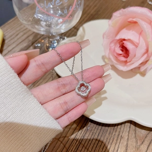 Makroaufnahme der silbernen Kleeblatt-Halskette mit tanzendem Stein und Pavé-Fassung