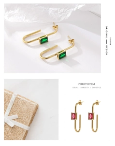 Detail of U-shaped gold earrings featuring emerald green and ruby red zircon stones