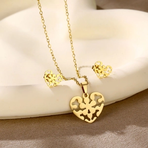 Detailed view of gold-plated hollow heart necklace and stud earrings set on a white tray