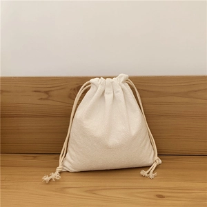 Close-up of minimalist cream cotton linen drawstring bag on a natural wooden table