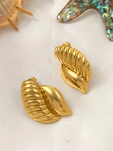 Detailed close-up of gold shell-shaped spiral earrings on a white seashell background