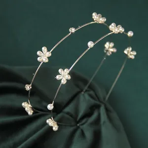 Dettaglio di un cerchietto dorato a doppio strato con fiori di perle e strass brillanti