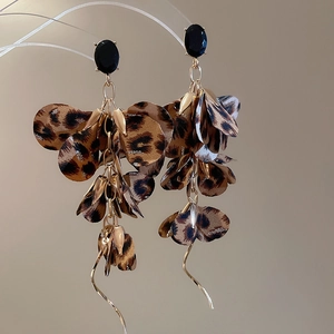 Detail showing long leopard print fabric petal earrings with black gemstone and gold accents