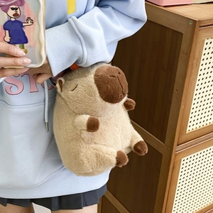 Brown plush Capybara backpack crossbody style shown on model in cozy home setting