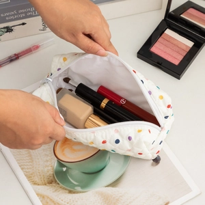 Detailed view of spacious quilted polka dot makeup bag filled with beauty products