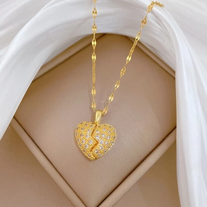 Detail of gold broken heart pendant with crystals in a beige jewelry box with fabric