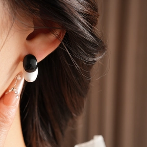 Detail view of monochrome oval resin earrings worn to show the actual size and fit