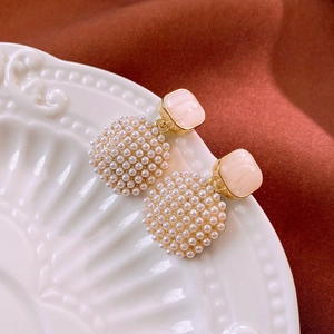 Detail shot of vintage style earrings with square resin top and small pearls on a white plate