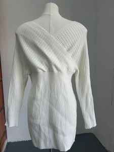 Detailed close-up of white knit dress featuring back cross V-neck and ribbed texture